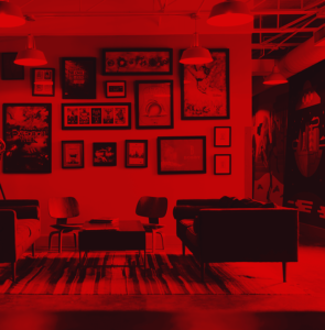 Red treated photo of the sitting area at ST8MNT with selected works on the wall.
