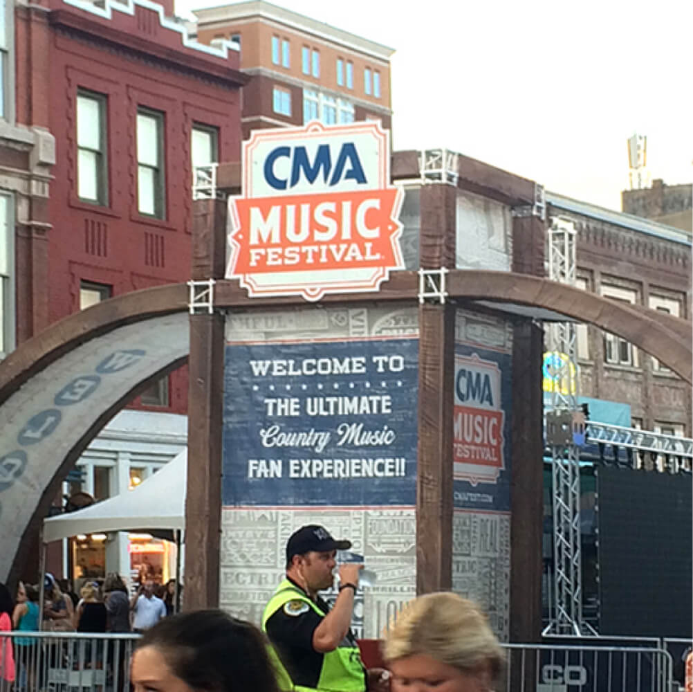 Photo of welcome signage and cop staying hydrated in the heat for CMA Music Festival in Nashville, Tennesee