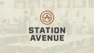 Station Avenue vertical logo in rust color with charcoal type on faded restaurant image background