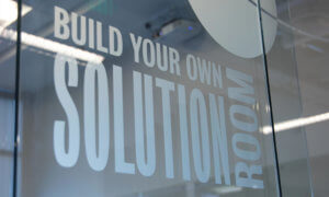 Frosted glass text signage on Build Your Own Solution Room door