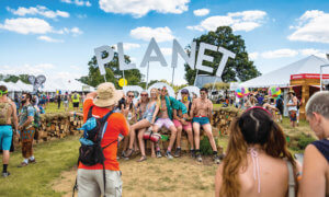 A group of festival attendees taking a photo in front of Planet Roo wooden letterforms