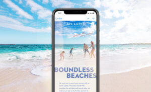 Mockup of iphone sits on top of beach image appearing to blend together. Example of an email header is shown. It reads "Boundless beaches, splash the day away!"