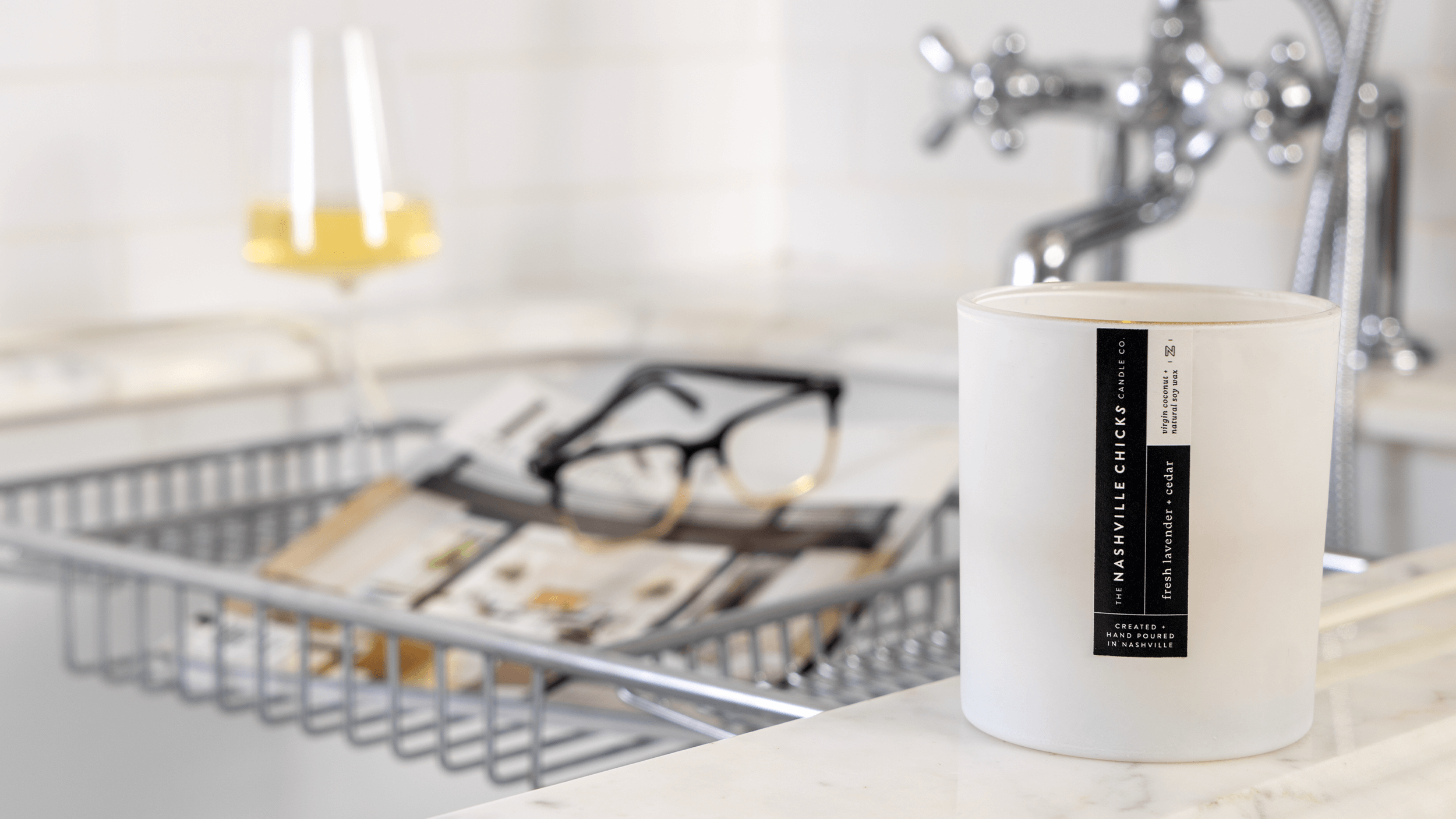 Photo of white NCCC candle in bathroom with glass of white and magazine