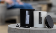 Black and white candle side by side with matches sitting on concrete, man in blue jeans blurred in background