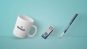 thread logo on a mug, thumb drive, and pen
