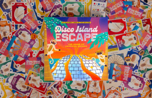 Disco Island Escape box resting on a pile of playing cards